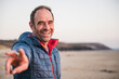 © Westend61 - Happy mature man gesturing peace sign at beach