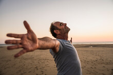 Smiling Mature Man With Arms Outstretched Enjoying At Beach