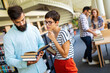 © NDABCREATIVITY - Happy university students studying with books in library. Group of multiracial people in college