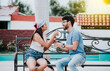 © IHERPHOTO - Young couple arguing sitting on a park bench, Concept of aggressive couples in the park. Upset couple arguing on a park bench. Man arguing with his girlfriend sitting in a park