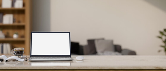 Workspace with laptop mockup and copy space on tabletop over blurred living room background