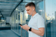 © stenkovlad - Young businessman man in headphones and with a phone in his hands