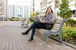 © Ivan Traimak - young woman working on a laptop online in the park on a bench, freelance work concept