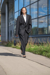 Wall Mural - Young sexy woman in male business suit posing on the street