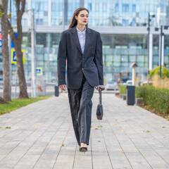 Wall Mural - Portrait of a young woman in a strict black male suit and handbag