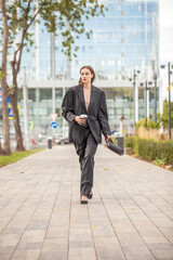 Wall Mural - Young sexy woman in male business suit posing on the street