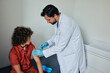Teenage boy during vaccinated by general practitioner in doctor's office. Child's immunizations and routine vaccinations