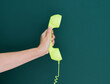 © xy - Woman hand holding vintage telephone receiver isolated on green background