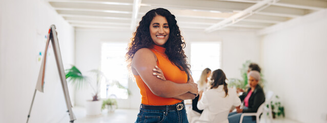 Wall Mural - Happy young businesswoman standing in a creative office