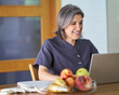 © Retamosa - a happy smiling woman working at the computer on the table has fruit and a fat meter