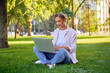 © Andrii - Businesswoman sitting grass summer park using laptop Business persone working remote. Outdoors