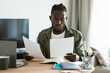 © Prostock-studio - Focused black male entrepreneur reading papers and business reports, checking documents while sitting at desk at home