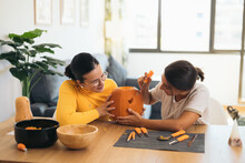 Women Making A Halloween Face On A Pumpkin