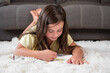 © herraez - Cheerful little girl lying on the floor drawing . High quality photography