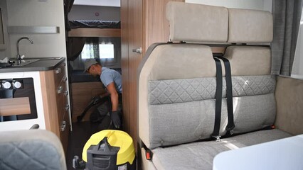 Wall Mural - Caucasian Worker Cleaning Modern Recreational Vehicle RV Motorhome Interior Using Vacuum. Camper Van Maintenance.