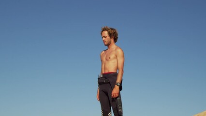 Wall Mural - Handsome strong young sportsman warming up his neck outdoors at the beach