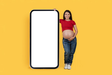 Happy Young Pregnant Female Leaning At Big Blank Smartphone With White Screen