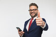 attractive man with glasses holding cellphone and making thumbs up gesture