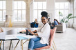 © BullRun - Happy black woman working on tablet in creative workspace