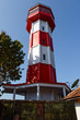 A Red and white lighthouse near a tree set against the sky