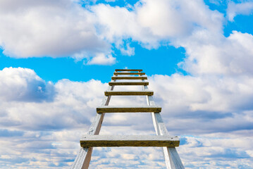 The way to success concept.Wooden ladder leading high up to the heaven.Blue sky and white clouds, success concept.Copy space.