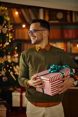 Wall Mural - Smiling man holding Christmas gift