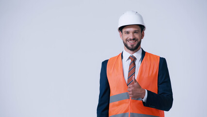 Poster - happy foreman in safety vest and helmet showing thumb up isolated on grey.