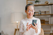 © NanSan - Relaxed asian mature 60s years old woman using smartphone, texting message at home.