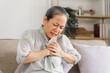 © NanSan - Senior asian mature woman heart disease, sitting on couch.