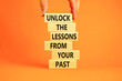 Lessons from your past symbol. Concept words Unlock the lessons from your past on wooden blocks. Bussinesman hand. Beautiful orange background. Business and lessons from your past concept. Copy space.