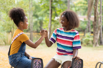 Wall Mural - Portrait of two happy African American child girl smiling and hold hands together at the playground