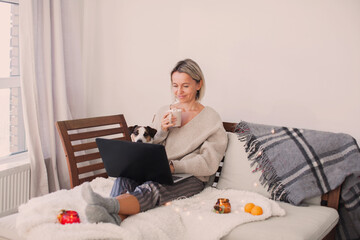 Wall Mural - Happy middle aged woman using her laptop on the sofa at home