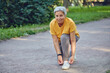 © Alex Tihonov - Elderly Asian woman ties shoelaces ready for jogging in park