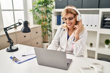 Poster - Middle age blonde woman wearing doctor uniform having medical teleconsultation at clinic