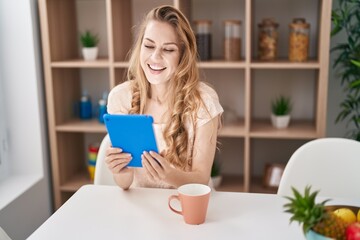 Poster - Young blonde woman using touchpad drinking coffee at home