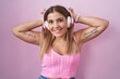 © Krakenimages.com - Young blonde woman listening to music using headphones posing funny and crazy with fingers on head as bunny ears, smiling cheerful
