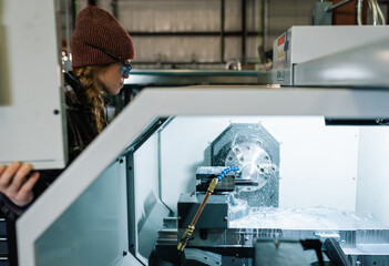 Wall Mural - Woman machinist uses CNC lathe machine in a factory setting