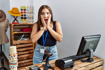 Poster - Young brunette woman holding banner with open text at retail shop afraid and shocked, surprise and amazed expression with hands on face