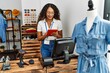 © Krakenimages.com - Young latin shopkeeper woman using touchpad working at clothing store.