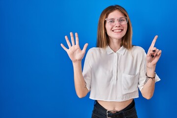 Sticker - Beautiful woman standing over blue background showing and pointing up with fingers number six while smiling confident and happy.