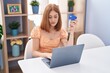 © Krakenimages.com - Young redhead woman using laptop and credit card sitting on table at home