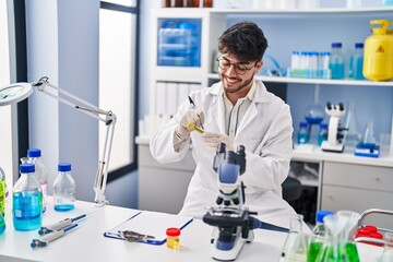 Canvas Print - Young hispanic man scientist smiling confident writing on test tube at laboratory