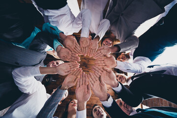 Wall Mural - Low angle below view portrait of attractive cheerful people experts putting arms together deal support at loft industrial interior indoors