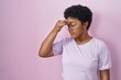 © Krakenimages.com - Young african american woman standing over pink background tired rubbing nose and eyes feeling fatigue and headache. stress and frustration concept.