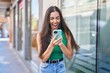 © Krakenimages.com - Young beautiful hispanic woman using smartphone with surprise expression at street