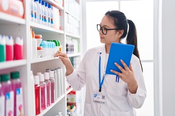 Wall Mural - Young chinese woman pharmacist using touchpad working at pharmacy