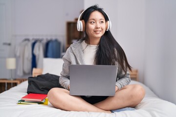 Sticker - Young chinese woman listening to music sitting on bed at bedroom