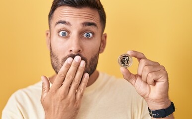 Sticker - Handsome hispanic man holding tron cryptocurrency coin covering mouth with hand, shocked and afraid for mistake. surprised expression