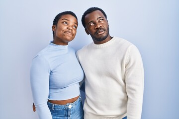 Sticker - Young african american couple standing over blue background smiling looking to the side and staring away thinking.