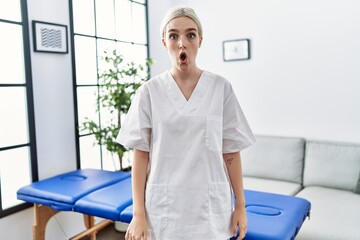 Poster - Young caucasian physiotherapy woman working at home scared and amazed with open mouth for surprise, disbelief face